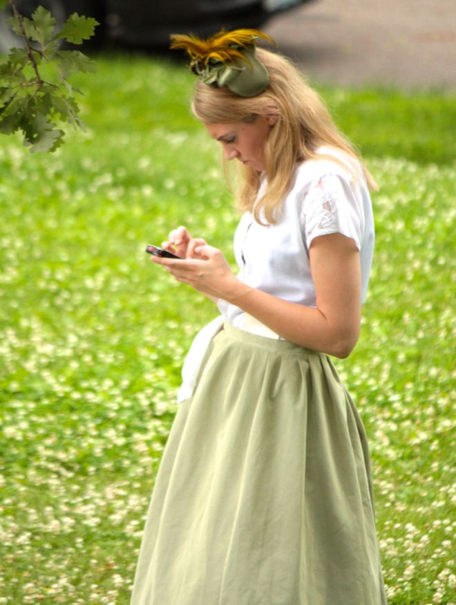 The actress in period clothing looking at her smartphone is an odd dichotomy.