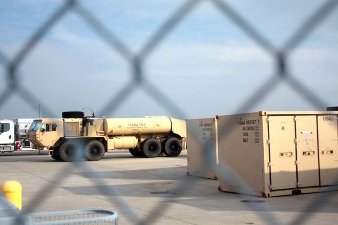 A National Guard fuel truck and storage lockers sit on the tarmac.