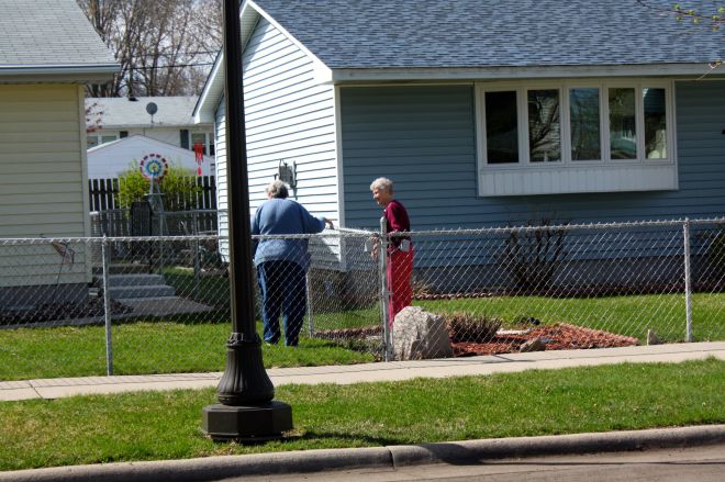 In a scene reminiscent of a Norman Rockwell painting, neighbors chat over the fence.