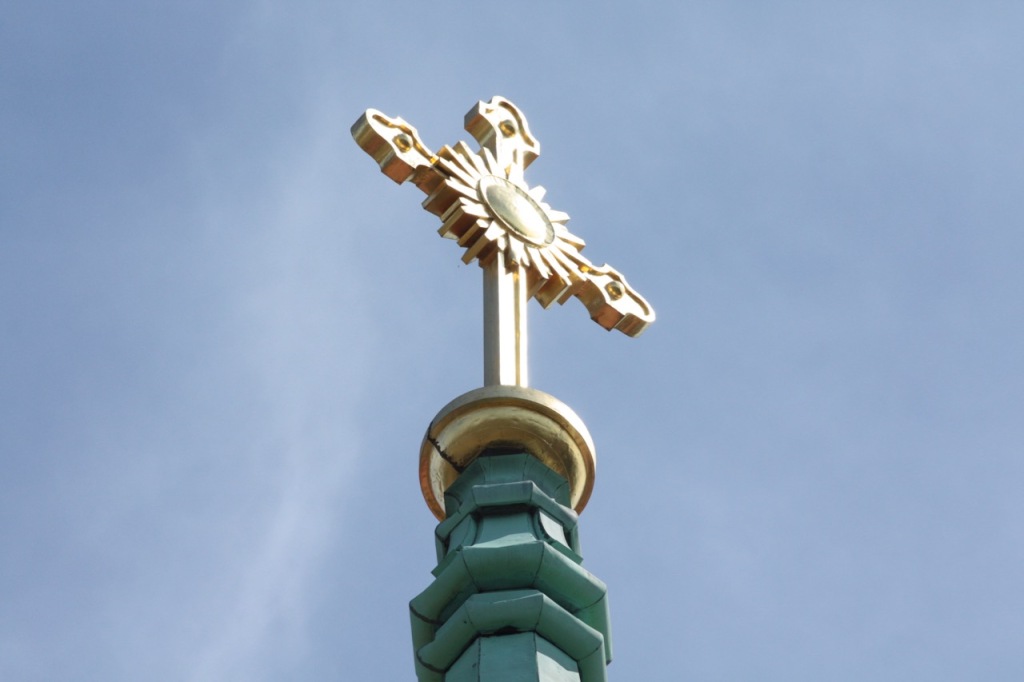 The gold cross at the top of the bell tower shimmered in the midday sun.