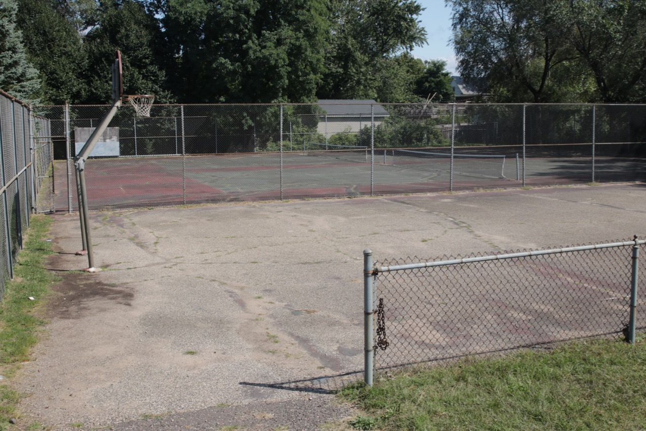 The worn basketball court, foreground, and the two tennis courts, background, at Mounds Park.